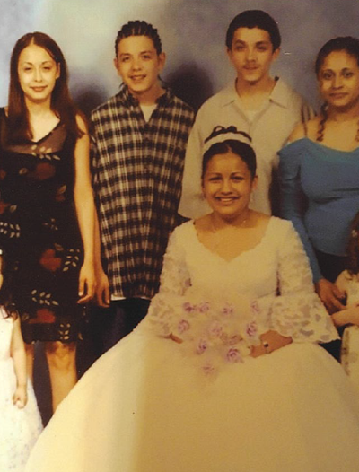 A family picture from a wedding, The bride is seated and surrounded by others: two teenagers and two adults.