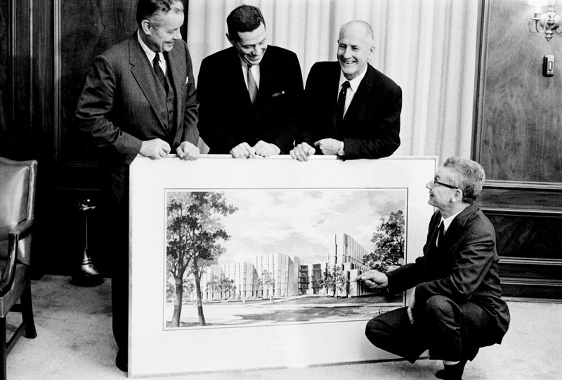 Fussler, Donnelley, and Regenstein hold large rendering of library as Fussler points to it.