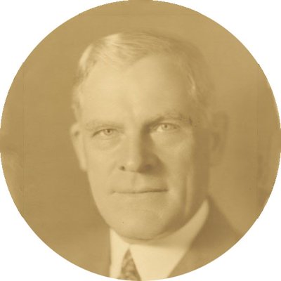 Black-and-white formal photographic portrait of Thomas E. Wilson, circa 1930s. He has short white hair and is wearing a suit and tie.